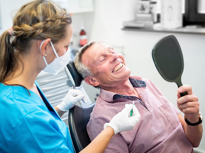 Zahnarzthelferin und Patient betrachten Zähne